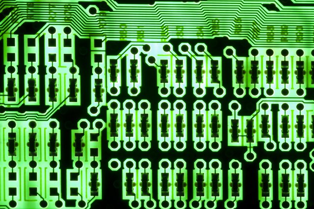 A close up of a back lit green and black electrical circuit board.