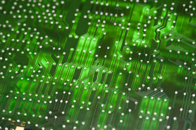 Green electronic circuit board glowing from inside, viewed in close-up selective focus and full frame for background concept