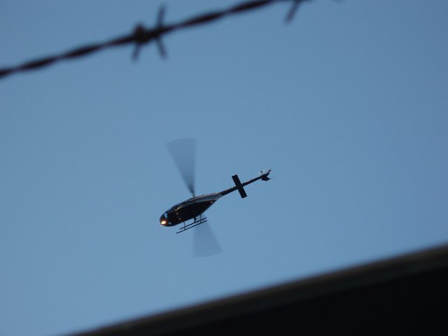 looking up towards a helecopter through a wire fence