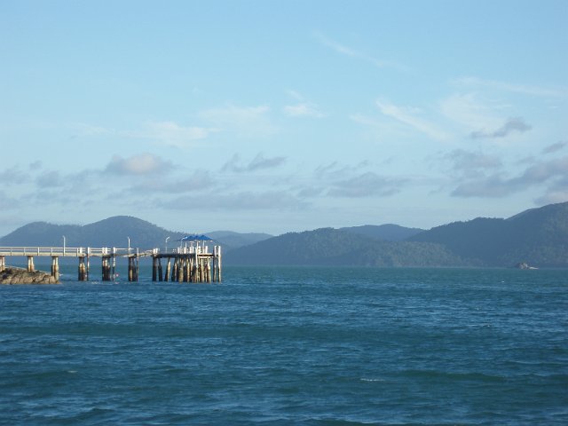 looking across open water to a white painted wooden jetty